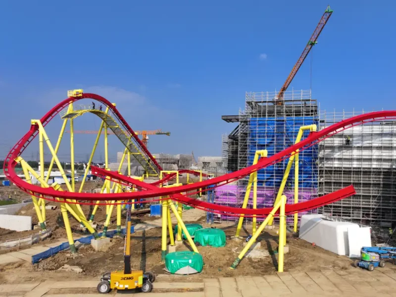 Das Bild zeigt eine rote Achterbahn mit gelben Stützen, die sich gerade für das Legoland Shanghai Resort im Bau befindet.